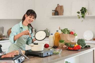 Genç kadın mutfakta erişte çorbası yapıyor.