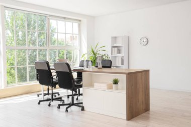 Masası, raf ünitesi ve palmiye bitkisi olan konferans salonunun içi.