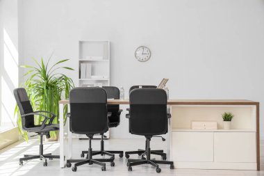 Masası, raf ünitesi ve palmiye bitkisi olan konferans salonunun içi.