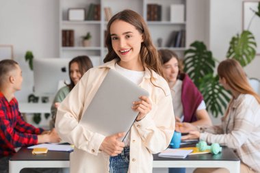 Kütüphanedeki sınıf arkadaşlarına karşı dizüstü bilgisayarı olan kız öğrenci