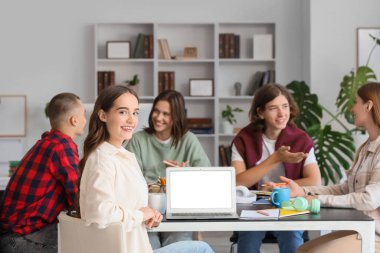 Boş dizüstü bilgisayarı ve kütüphanedeki sınıf arkadaşları olan bir kız öğrenci.