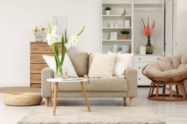 Kanepe, dolap ve vazolarda gladyatör çiçekleri olan oturma odasının içinde.