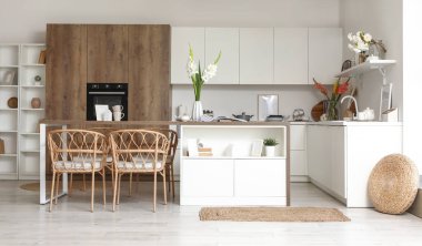 Mutfağın içinde masa, tezgah ve vazolarda gladyatör çiçekleri var.