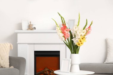 Oturma odasındaki masanın üzerinde gladiolus çiçekleri olan vazo.
