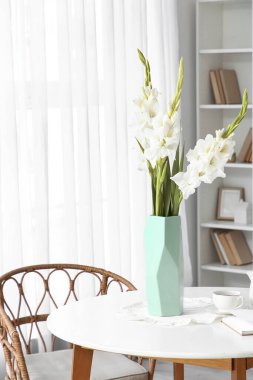 Yemek masasının üzerinde gladiolus çiçekleri olan vazo.