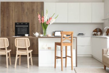 Mutfağın içinde masa, tezgah ve gladyatör çiçekleri var.