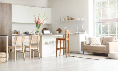 Mutfağın içinde masa, tezgah ve gladyatör çiçekleri var.