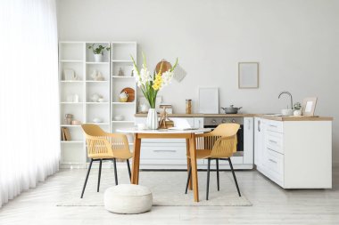 Tezgahları, yemek masası ve gladyatör çiçekleriyle aydınlık mutfağın içi.