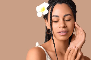 Güzel Afro-Amerikalı kadın bej arka planda tesisat çiçeği olan, yakın plan