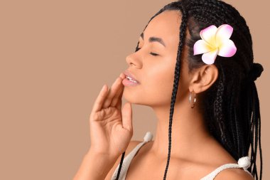 Güzel Afro-Amerikalı kadın bej arka planda tesisat çiçeği olan, yakın plan