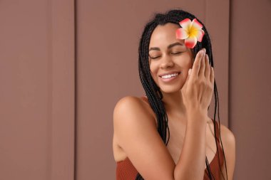 Kahverengi arka planda tesisat çiçeği olan güzel bir Afro-Amerikalı kadın.