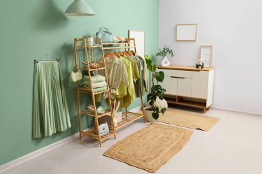 Askısı, aksesuarı ve bitkileri olan bir giyim mağazası.