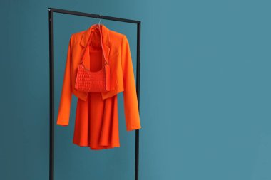 Turuncu elbiseli raflar ve mavi arka planda çantalar.