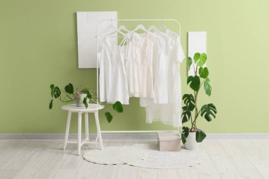 Beyaz elbiseli ve palmiye bitkilerli bir giyim mağazası.