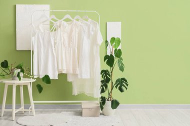 Beyaz elbiseli ve palmiye bitkilerli bir giyim mağazası.