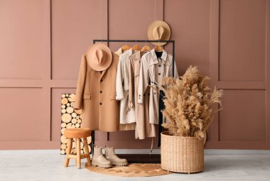 Elbise mağazasında kahverengi duvarın yanında şapka ve çim pampası olan bir askılık.
