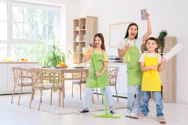 Genç anne çocuklarıyla mutfakta temizlik malzemesi taşıyor.