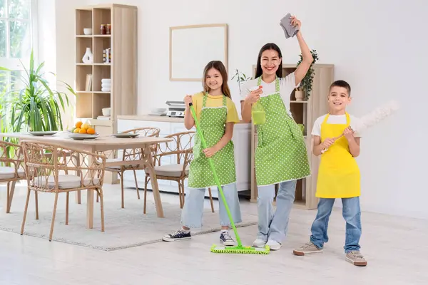 Genç anne çocuklarıyla mutfakta temizlik malzemesi taşıyor.