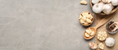 Taze sarımsaklı ahşap kaseler ve gri arka planda biberler.