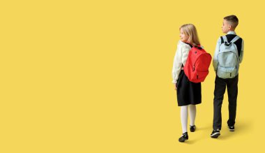 Sırt çantalı küçük öğrenciler sarı arkaplan ve metin için yer var.