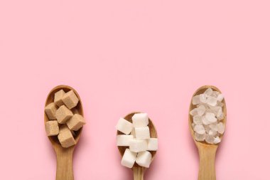 Pembe arka planda farklı tipte şeker içeren kaşıklar