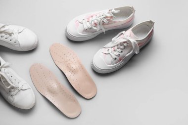 Bir çift ortopedik taban ve açık arkaplanda şık bayan ayakkabıları.