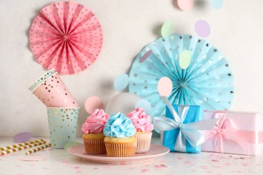 Beyaz grunge arka planına karşı hediye kutuları ve süslemeleri olan lezzetli kekler. Cinsiyet ortaya çıkan parti kavramı