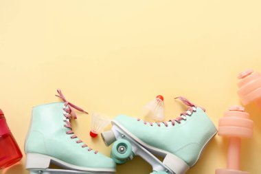 Bir çift tekerlekli paten, dambıl ve badminton mekik horozu.