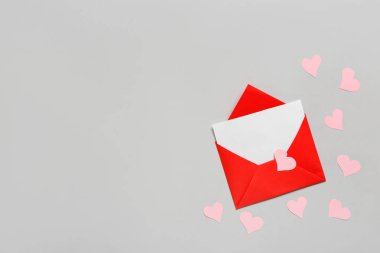 İçinde boş kart ve gri arka planda pembe kağıt kalpler olan bir zarf. Sevgililer Günü kutlaması