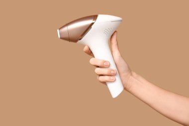 Kahverengi arka planda modern fotoğraf makinesi olan kadın eli.