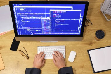 Geceleri masadaki bilgisayarla çalışan programcı, üst görünüm