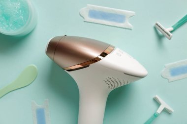 Turkuaz arka planda fırça, balmumu şeritleri ve jiletle modern fotoepilatör