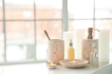 Diş fırçaları, mumlar ve beyaz küvet tepsisindeki farklı kozmetikler.