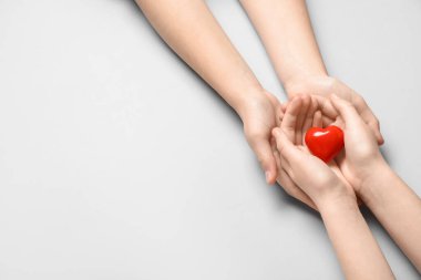 Gri arka planda kırmızı kalpli kadın ve çocuğun elleri