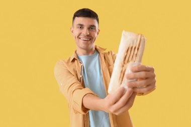 Sarı arka planda lezzetli donör kebabı olan mutlu genç adam.