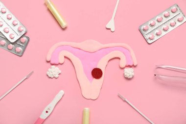 Pembe arka plan üzerinde hamilelik testi, haplar ve Pap smear test araçları ile plasticine uterus