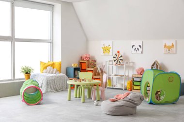 Modern çocuk odasının içinde masa ve tünel oyunu.