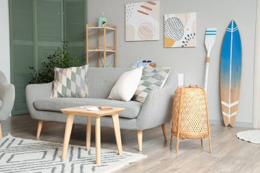 Gri kanepe ve sörf tahtasıyla modern oturma odasının içinde.