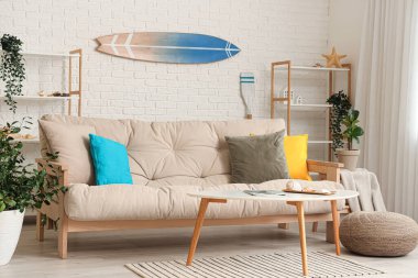 Beyaz kanepe ve sörf tahtasıyla aydınlık oturma odasının içinde.