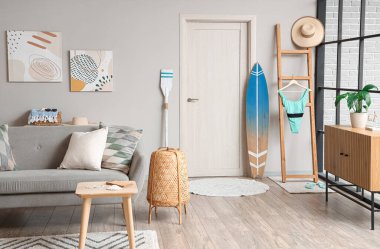 Gri kanepe ve sörf tahtasıyla modern oturma odasının içinde.