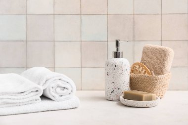 Temiz yumuşak havlu yığını, bir şişe kozmetik ürün ve banyo duvarının yanındaki sabun kalıbı.