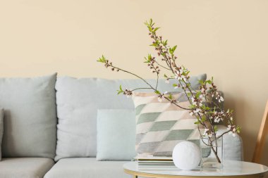 Kanepesi olan güzel bir oturma odası ve vazo dolusu dalları olan bir kahve masası.