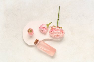 Kozmetik yağ şişesi, alçı standı ve hafif grunge arka planda güller ile kompozisyon