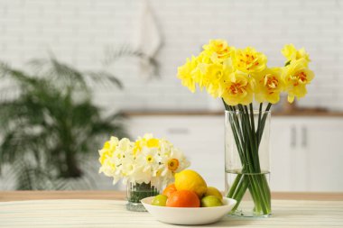 Mutfaktaki masada nergis ve meyve buketleri, yakın plan.