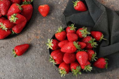 Koyu arkaplanda taze çilekli tabaklar.