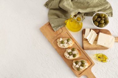 Tahta tahta tahta ekmek dilimleri lezzetli peynir ve beyaz arka planda zeytinler.