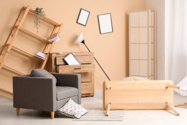 Koltuğu ve ters dönmüş masası olan dağınık bir oturma odası.