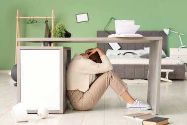 Yatak odasında deprem sırasında masanın altında saklanan kadın.