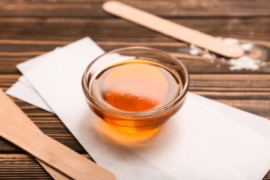 Cam kâse şekerleme macunu, balmumu şeritleri ve tahta arka planda çubuklar.