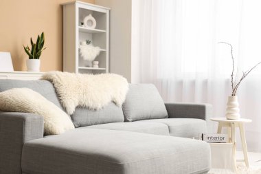 Gri kanepeli, sehpalı, raf üniteli ve resimli şık bir oturma odası.